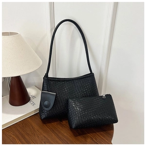 Detail of black woven shoulder bag set with matching inner pouch on wooden table