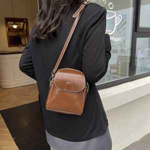 Vintage brown crossbody phone bag with white stitching shown on a model outdoors