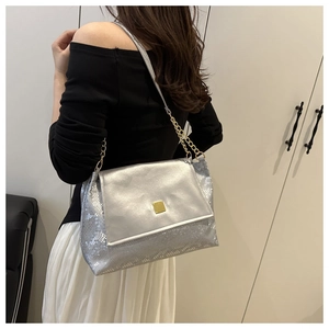 Detail of silver square crossbody bag featuring snake pattern and gold metal lock
