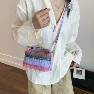 Colorful woven crossbody bag with purple strap and ethnic pattern shown on a model