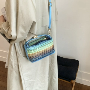 Rainbow woven straw handbag with blue leather straps shown as a stylish crossbody bag