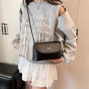 Petit sac carré en cuir noir avec nœud argenté porté avec une tenue décontractée chic