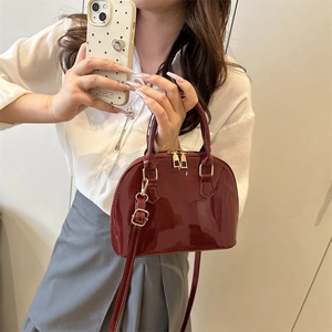 Chic dark red patent leather shell bag with gold hardware and adjustable strap