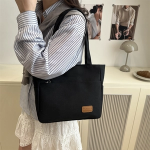 Black canvas tote bag with front zipper pocket and leather logo for casual daily commute