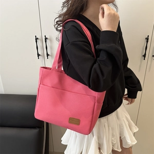 Pink large capacity canvas tote bag with brown leather logo patch carried by model