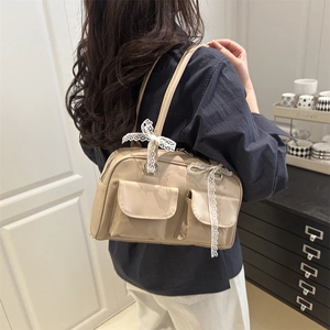 Beige multi-pocket shoulder bag with lace bow decoration in a lifestyle setting