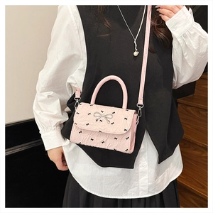 Détail du sac bandoulière rose avec nœuds noirs et fermoir argenté en forme de nœud