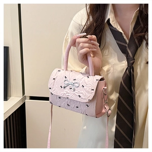 Dettaglio della mini borsa rosa a pieghe con fiocco in metallo argento e motivo nero