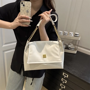 Chic white flap shoulder bag with gold chain strap held by model in modern home setting