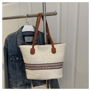 Detail of hand-woven tote bag with brown floral pattern and leather straps