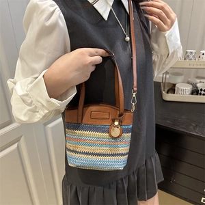 Rainbow striped woven bucket bag with brown leather straps and adjustable shoulder belt
