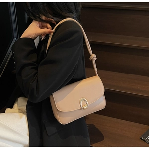 Detail of nude leather shoulder bag with gold horseshoe buckle and knotted strap