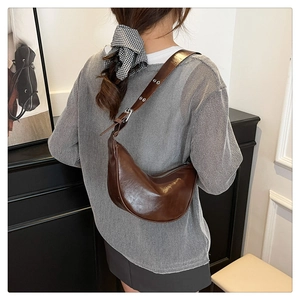 Detail of dark brown crescent bag with eyelet adjustable strap on model's shoulder