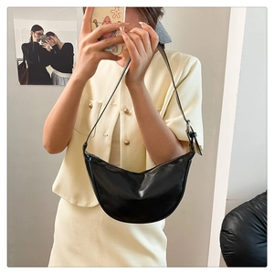 Mirror selfie showing the fit of a glossy black crescent shoulder bag with silver hardware