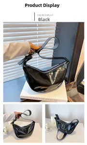Detail of black glossy leather hobo bag featuring silver hardware and wide shoulder strap