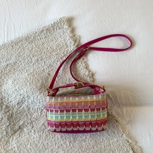 Dettaglio della borsa a tracolla intrecciata fucsia con trama geometrica e chiusura in metallo