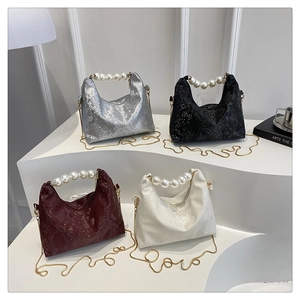 Detail of elegant snake skin texture handbags with pearl handles and gold chain straps
