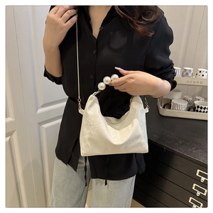 Dettaglio borsa bianca con manico di perle oversize e tracolla a catena dorata