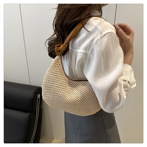 Nahaufnahme der beigen Strohtasche mit braunem Lederriemen und dekorativem Knotendetail
