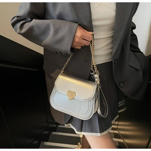 Close-up of silver mini flap bag with gold heart-shaped lock and metal chain strap