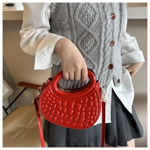 Detail of bright red crescent handbag with embossed 3D texture and gold metal hardware