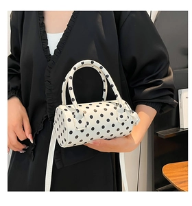 Detailed shot of mini white cylindrical bag with black polka dots and PU top handles