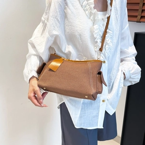 Retro brown canvas underarm shoulder bag with leather trim worn by a model