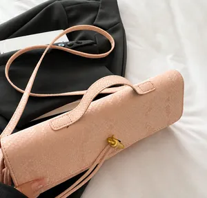 Roze baguette tas in slangenleerlook met gouden draaislot en smalle schouderriem