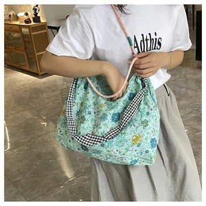 Detailed close-up of floral canvas tote bag featuring green prints and woven straps