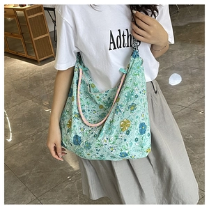Detail view of mint green floral canvas hobo bag with colorful striped shoulder strap