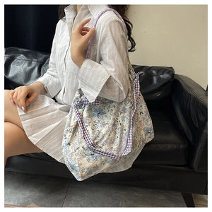 Floral canvas tote bag with purple checkered bow shoulder strap shown on a model
