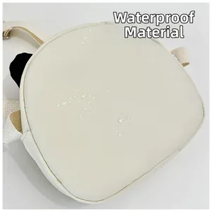 Gros plan du tissu imperméable beige avec gouttes d'eau sur un sac bandoulière mignon