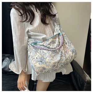 Detail view of floral canvas tote bag showing purple braided rope handle and blue flower print