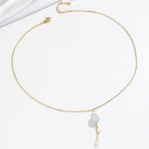 Vue détaillée du collier doré avec perle verte et pendentifs en perles blanches