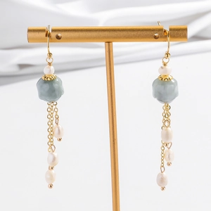 Détail de boucles d'oreilles vintage avec perles de jade, glands dorés et perles baroques