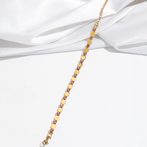 Detail of gold bracelet featuring alternating pink zircons and polished metal discs