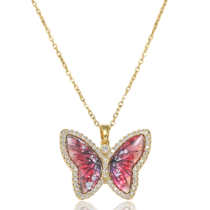 Close-up of golden necklace with pink enamel butterfly pendant and sparkling zircon stones