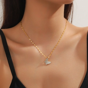Detail of a gold butterfly necklace with sparkling crystals worn on a model's neck