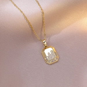 Gold titanium necklace featuring a geometric zircon-encrusted castle pendant on silk