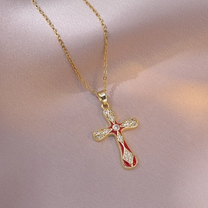 Goldene Kreuzkette mit roter Emaille und Zirkonia auf rosa Seide