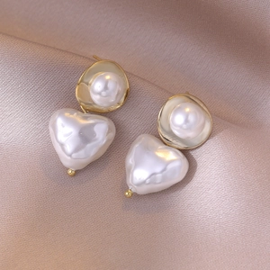 Elegant gold-tone drop earrings with round and heart-shaped pearls on champagne silk