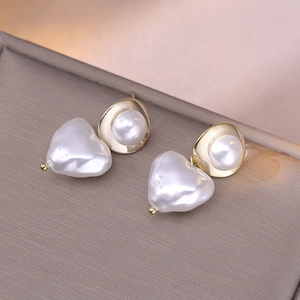 Elegant gold heart-shaped pearl earrings with 925 silver needles on a jewelry box