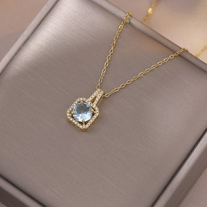 Close-up of gold necklace with a square pendant featuring a blue zircon and micro-pave crystals