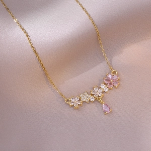Collier doré avec fleurs en zircone rose et pendentif goutte sur fond de soie rose