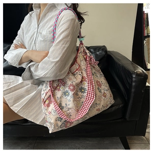 Detail view of floral canvas tote bag with red checkered strap and soft fabric texture