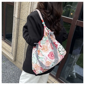 Close-up of floral canvas tote bag with pleated texture and black check ribbon detail