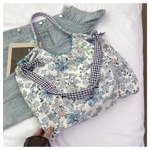 Detail of floral tote bag with purple plaid straps and braided rope handles on denim