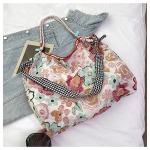 Close-up of floral canvas tote with red trim and stylish black and white checkered straps