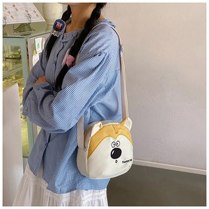 Détail d'un joli sac bandoulière en toile jaune en forme de chien avec sangle en tissu blanc