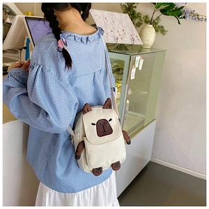 Close-up of a cute cream capybara crossbody bag worn by a girl in a cozy cafe